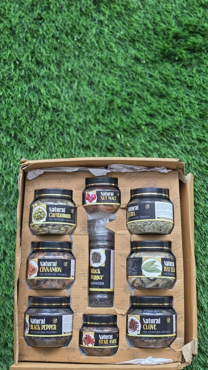 Open box holding eight labelled spice jars and a black pepper grinder
