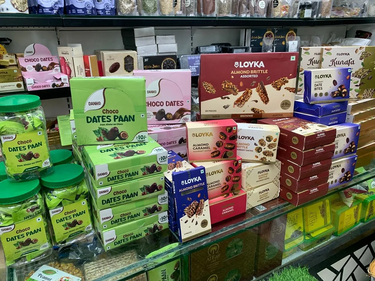 A shop shelf stacked with chocolate dates and almond brittle gift boxes