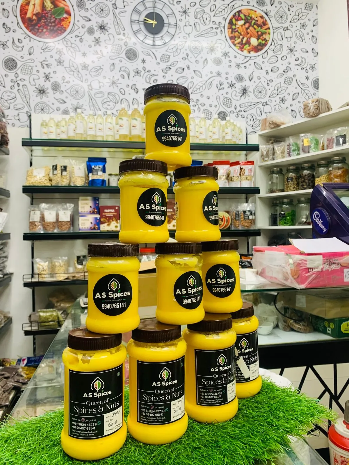 A pyramid of A S Spices ghee jars with black labels on the shop counter