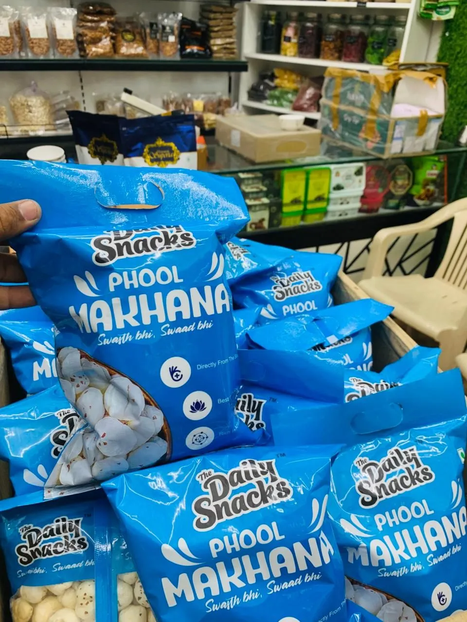 Blue sealed packs of phool makhana stacked in a box