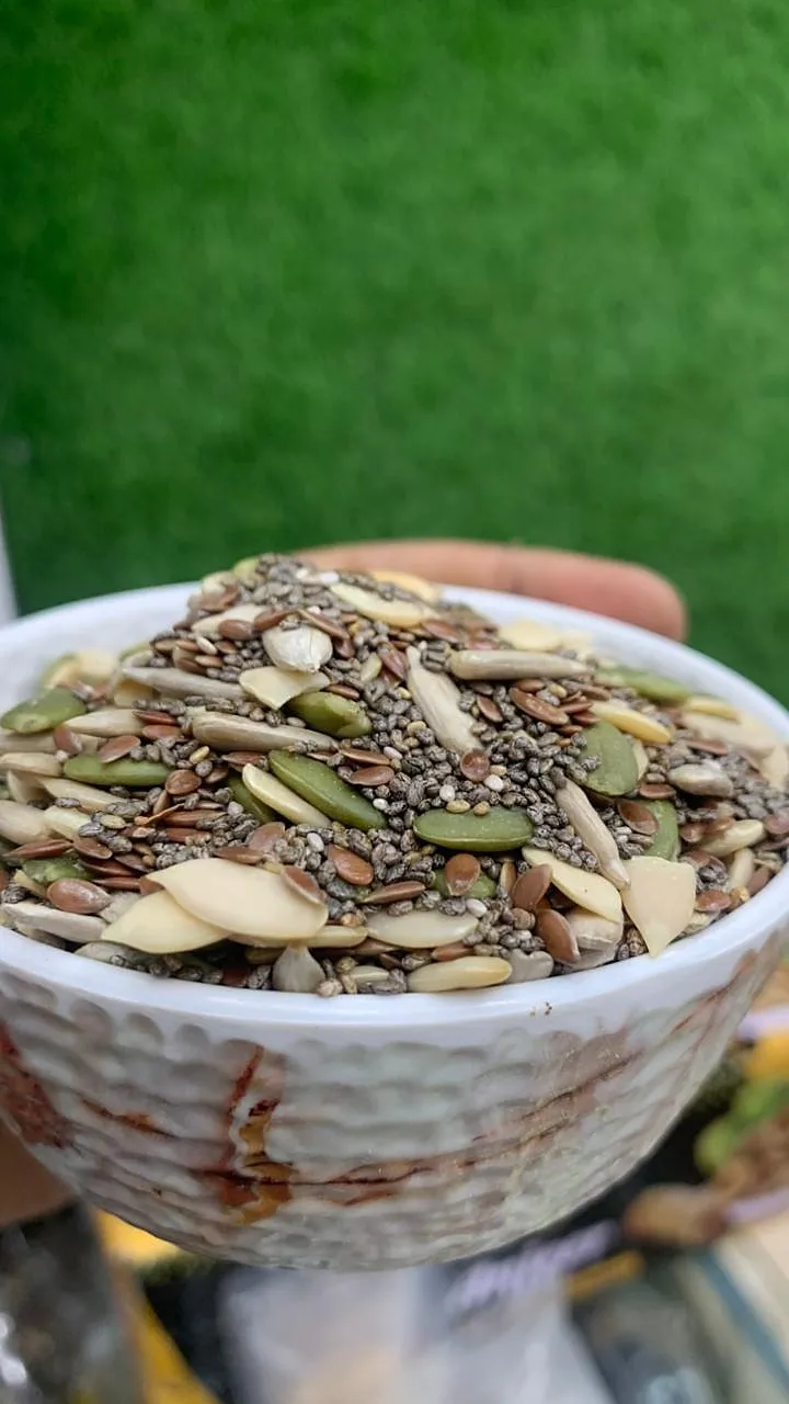 A bowl of mixed seeds held in a hand
